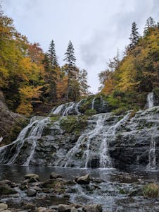 Picturesque waterfall amidst vibrant autumn foliage on Cape Breton Island, Nova Scotia.